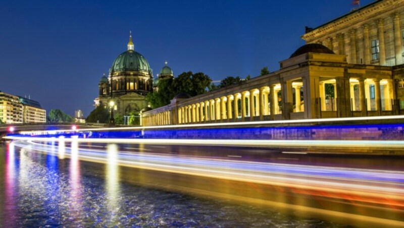 Ein Schiff fährt in Berlin an dem hell erleuchteten Arkadengang an der Alten Nationalgalerie auf der Museumsinsel in Berlin vorbei. (Bild: APA/dpa)