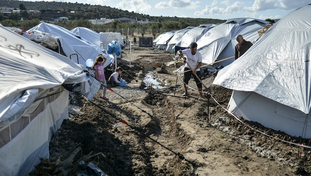 Migranten müssen im Ausweichlager Kara Tepe auf Lesbos Gräben schaufeln, damit Regen besser abrinnen kann. (Bild: AP)