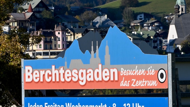 Ein Schild mit der Aufschrift „Berchtesgaden - Besuchen Sie das Zentrum“ hängt vor der Kulisse der Ortschaft. (Bild: APA/dpa/Peter Kneffel)