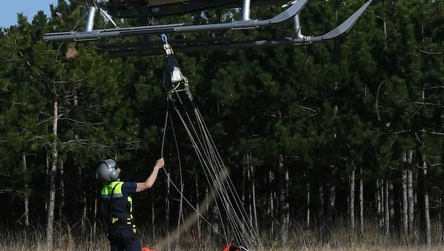 Ein Flightoperator der Flugpolizei befestigt einen Löschwasserbehälter unter dem Helikopter (Bild: Huber Patrick)