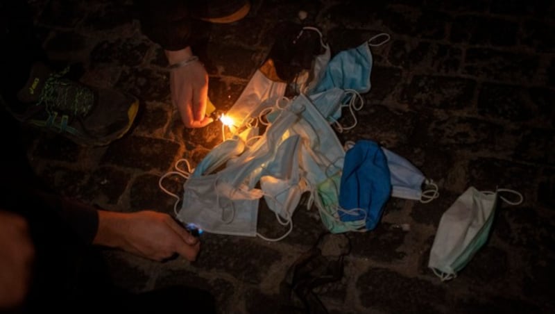 Wie schon am Nationalfeiertag in Wien wurden auch in anderen Städten - wie hier in Barcelona - Masken verbrannt. (Bild: AP Photo/Emilio Morenatti)