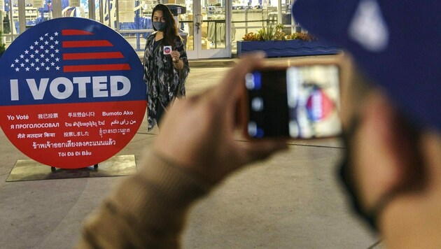 Eine Wählerin lässt ein Foto mit einem „Ich habe gewählt“-Schild von sich schießen. (Bild: AP)