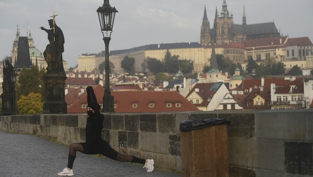 Eine Sportlerin auf der Karlsbrücke in Prag trägt auch beim Laufen vorschriftsmäßig eine Maske. (Bild: AFP )
