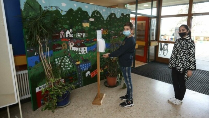 Kinder am Eingang zur Schule desinfizieren sich die Hände. (Bild: Daniel Scharinger)