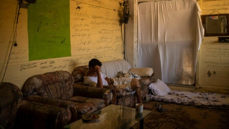 Ein Mann sitzt auf einem Sofa in einem verlassenen Haus unweit des Camps Kara Tepe. (Bild: APA/AFP/ANGELOS TZORTZINIS)