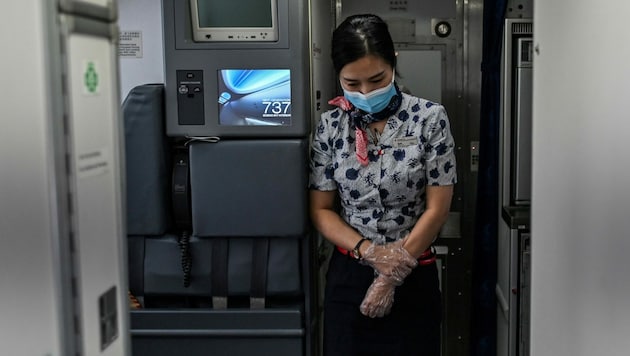 Diese chinesische Flugbegleiterin sollte laut Empfehlung der Flugbehörde auch Schutzanzug und Windel tragen. (Bild: AFP)