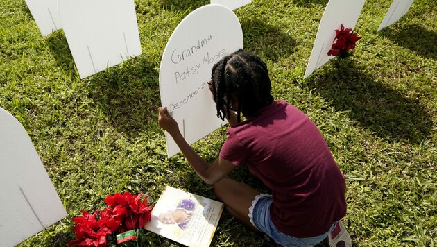 Eine Enkelin gedenkt ihrer infolge einer Covid-Erkrankung verstorbenen Großmutter auf einem symbolischen Friedhof für Corona-Opfer in Florida. (Bild: AP)