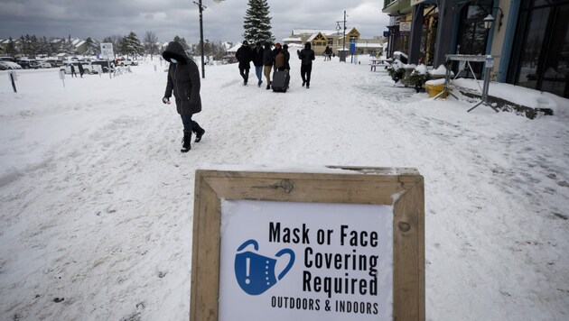 Ein Schild weist im Blue Mountain Ski Resort auf die Maskenpflicht auch im Freien hin. (Bild: AP)
