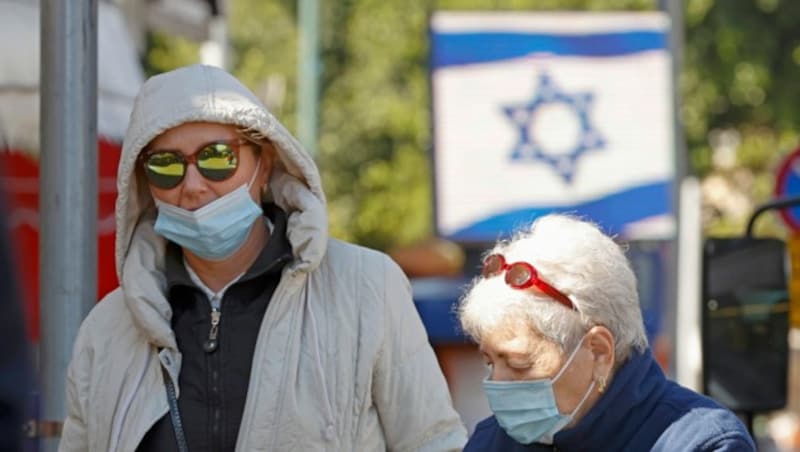Menschen mit Mund-Nasen-Schutz in der israelischen Küstenstadt Netanya zwischen Tel Aviv und Chadera (Bild: AFP)