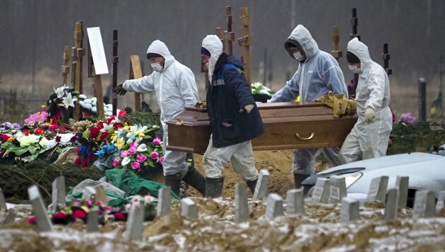 Totengräber bei St. Petersburg tragen den Sarg eines Corona-Opfers. (Bild: AP)