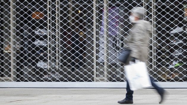 Eine Frau mit einer Einkaufstasche geht an einem geschlossenen Geschäft in der Stuttgarter Königsstraße vorbei. Der Handel rechnet nicht mit einem raschen Ende der coronabedingten Ladenschließungen. (Bild: APA/DPA/TOM WELLER)