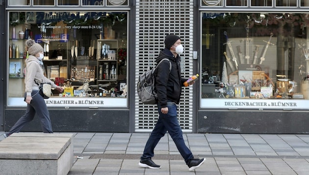 Mittlerweile ein gewohntes Bild in Österreich: Fußgänger gehen mit Mund-Nasen-Schutz an geschlossenen Geschäften vorbei. (Bild: AP)