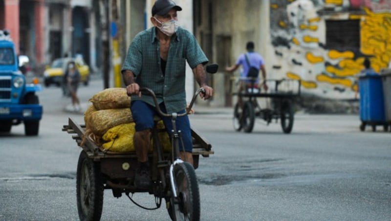 A man wearing a face mask transports bags with vegetables for sale in Havana, on January 21, 2021. - Cuban investigators have centered in the task of developing the first vaccine against COVID-19 conceived and produced in Latin America. (Photo by YAMIL LAGE / AFP) (Bild: AFP)