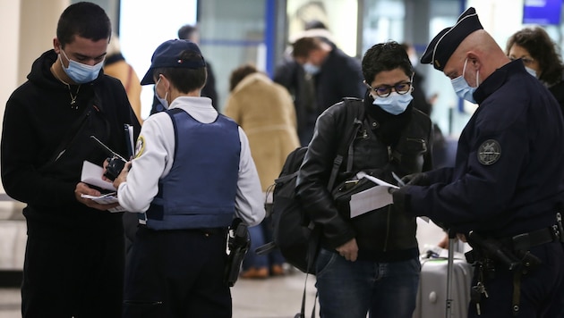 Französische Polizisten kontrollieren am Flughafen in Ajaccio negative Corona-Testbescheide von Reisenden. (Bild: AFP)