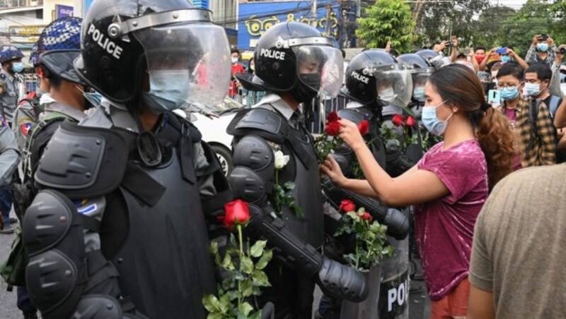 Demonstrantinnen verteilten Blumen an die Polizei. (Bild: APA/AFP/STR)