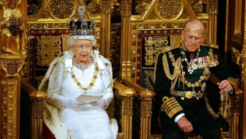 Königin Elizabeth II. sitzt neben ihrem 2021 verstorbenen Ehemann Prinz Philip, Herzog von Edinburgh, als sie während der Staatseröffnung des Parlaments in London am 18. Mai 2016 die Eröffnungsrede hält. (Bild: ALASTAIR GRANT / AFP / picturedesk.com)