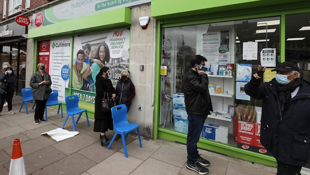 Menschen warten außerhalb einer Apotheke in London auf ihre Corona-Teilimpfung. (Bild: AP)