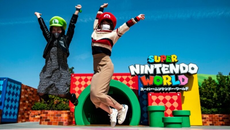 In this picture taken on March 17, 2021, fans of Universal Studio Japan pose at the entrance of the Super Nintendo World, during a media preview of the theme park in Osaka. (Photo by Philip FONG / AFP) (Bild: AFP)