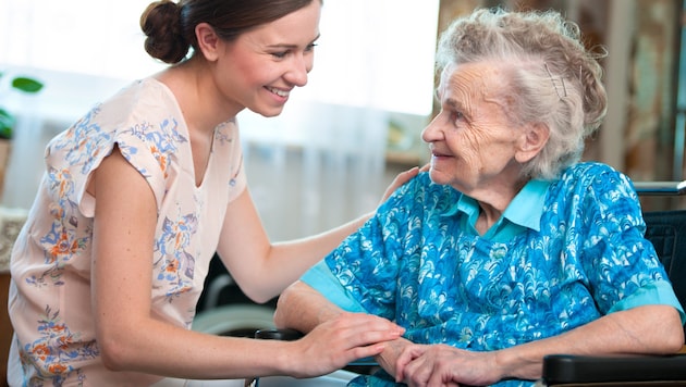 A caregiver with a senior citizen (Bild: ©Alexander Raths - stock.adobe.com)