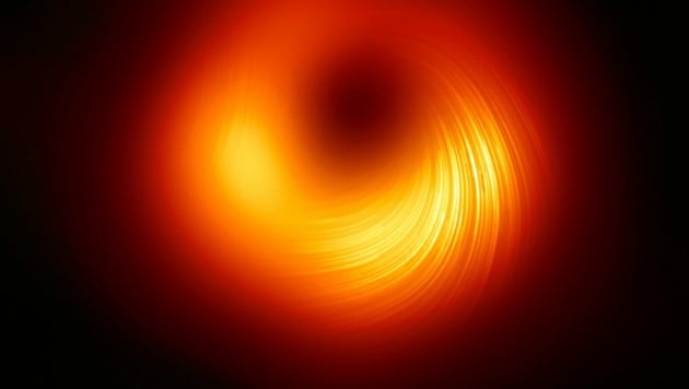 Dieses Bild zeigt die Ansicht der Polarisation des Schwarzen Lochs in M87. Die Linien markieren die Ausrichtung der Polarisation, die mit dem Magnetfeld um den Schatten des Schwarzen Lochs zusammenhängt. (Bild: EHT Collaboration)
