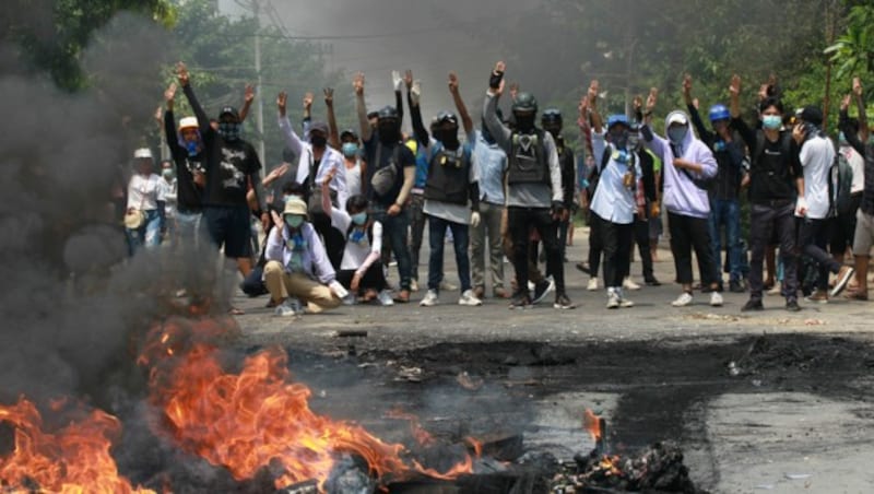 Menschen, die in Yangon gegen die Machtübernahme des Militärs demonstrieren, strecken drei Finger als Zeichen des Protests in die Luft. Sicherheitskräfte gehen äußerst brutal gegen Demonstranten vor. (Bild: AP)