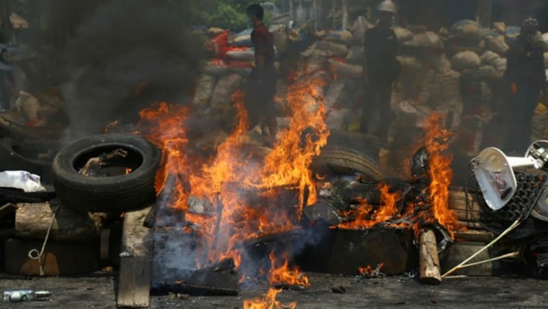 Demonstranten setzen Autoreifen in Brand (Bild: AP)