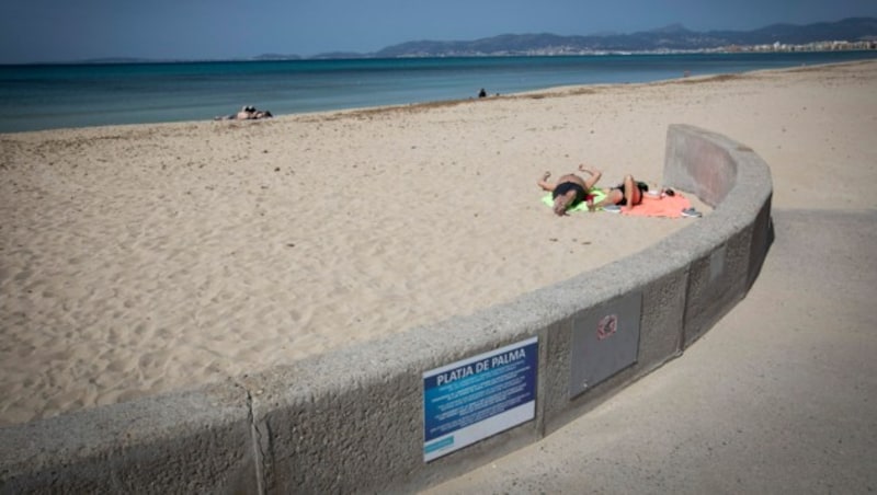 Touristen auf Mallorca genießen am fast menschenleeren Strand die Sonne. (Bild: AFP)