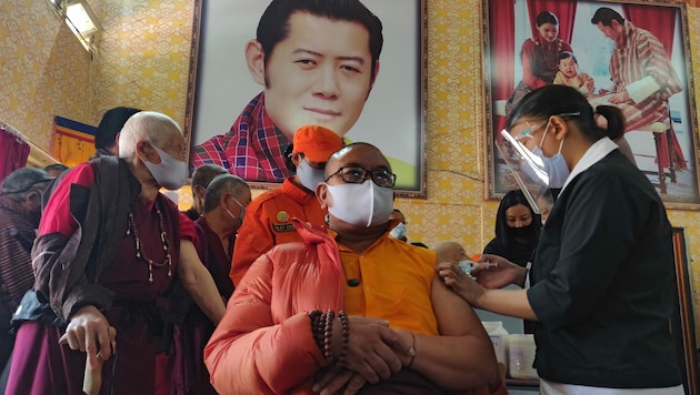 Ein Mönch wird in Bhutan vor einem Porträt von König Jigme Khesar Namgyel Wangchuck geimpft. (Bild: APA/AFP/Upasana DAHAL)