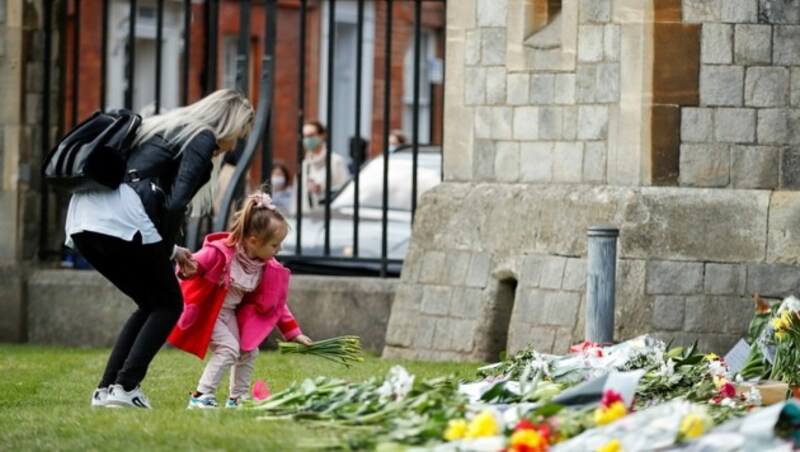 Ein kleines Mädchen legt im Gedenken an Prinz Philip Blumen vor die Tore von Windsor Castle. (Bild: ANDREW BOYERS / REUTERS / picturedesk.com)