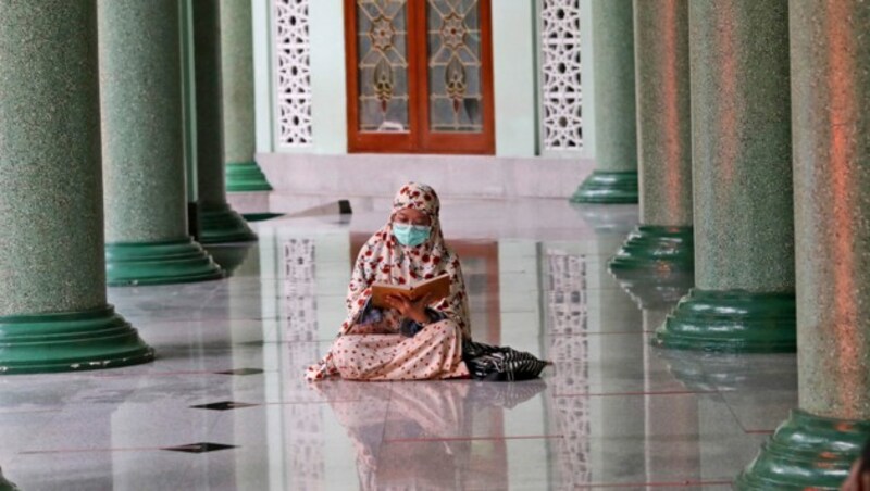 Eine Frau mit Mundschutz liest in einer Moschee in Jakarta (Indonesien) den Koran. (Bild: AP Photo/Tatan Syuflana)