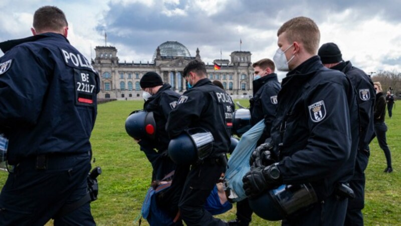 Polizisten tragen einen Mann weg, der vor dem Reichstagsgebäude in Berlin gegen Corona-Maßnahmen demonstrierte. (Bild: APA/AFP/John MACDOUGALL)