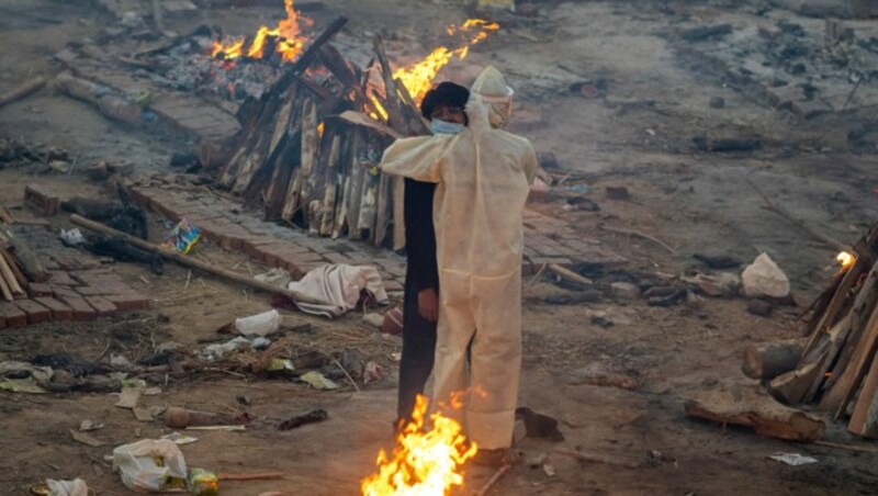 Angehörige trauern auf einem Feld, die Leichen werden in provisorischen Krematorien verbrannt. (Bild: APA/AFP/Jewel SAMAD)