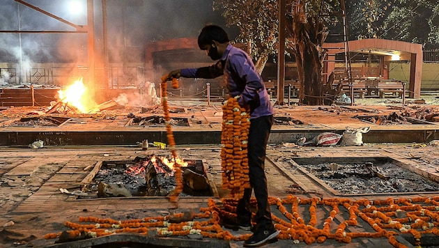 Ein Trauernder legt Blumenkränze ab. Auf dem Subkontinent wütet derzeit die Pandemie. (Bild: SAJJAD HUSSAIN)