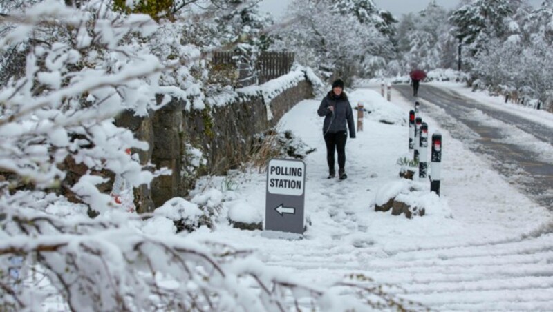 Eine Frau geht bei Schneefall zur Parlamentswahl in der Nähe von Inverness in Schottland. (Bild: AP)