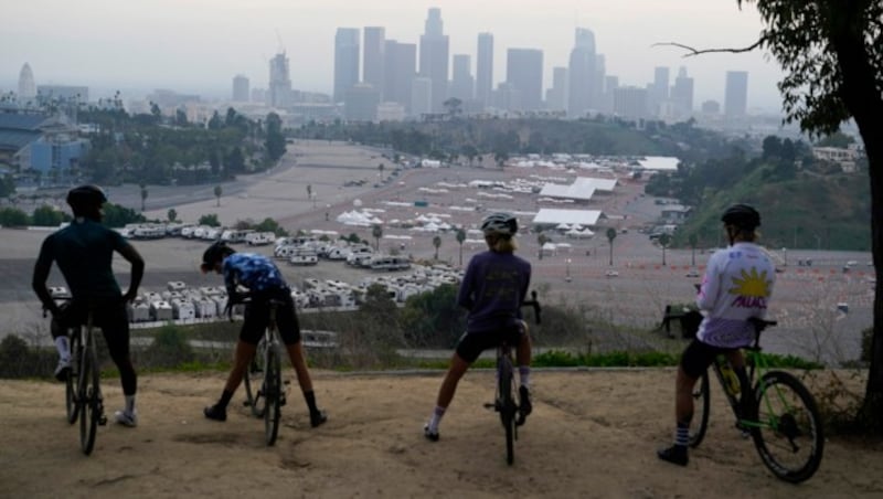 Radfahrer bestaunen das Dodger Stadium in Los Angeles, in dem nun geimpft wird. (Bild: AP Photo/Marcio Jose Sanchez, File)