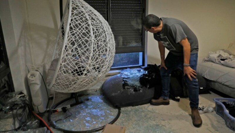 Ein Mann inspiziert zerbrochene Fensterscheiben nach einem Raketeneinschlag am Rand von Jerusalem. (Bild: APA/AFP/Gil COHEN-MAGEN)