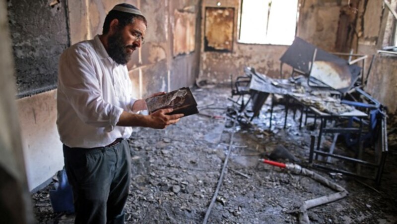 Ein Rabbi begutachtet den Brandschaden in seiner Synagoge. (Bild: APA/AFP/AHMAD GHARABLI)