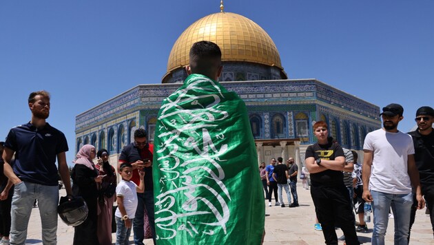 A young person with the flag of the radical Islamic group Hamas in front of the Dome of the Rock in Jerusalem (Bild: AFP)