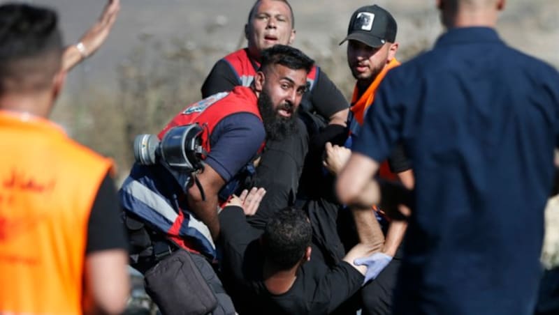 Palästinensische Rettungskräfte transportieren einen verletzten Demonstranten ab. Am Dienstag gab es wieder Zusammenstöße in Gaza und Ost-Jerusalem. (Bild: AFP)