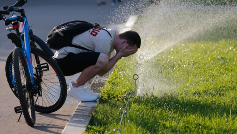 Angesichts des heißen Wetters braucht dieser russische Radfahrer eine Abkühlung. (Bild: AP)