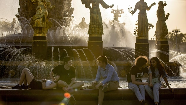 Diese jungen Russen genießen die ungewöhnlich warme Abendsonne in Moskau. (Bild: Associated Press)