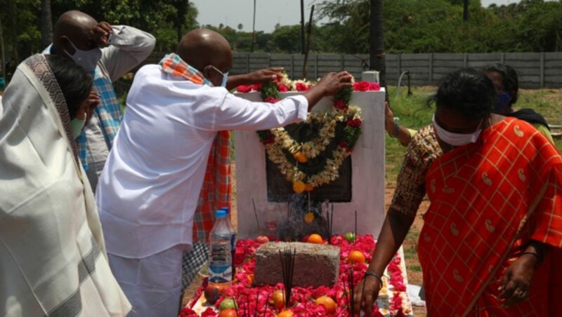 In der Nähe der indischen Stadt Hyderabad legen Menschen Blumen am Grab eines an Covid-19 verstorbenen Verwandten nieder. (Bild: AP)