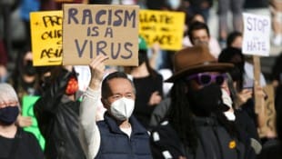 Ein Mann protestiert gegen anti-asiatische Vorurteile bei einer Demo in Seattle im März. „Rassismus ist ein Virus“ steht auf dem Schild. (Bild: APA/AFP/Jason Redmond)