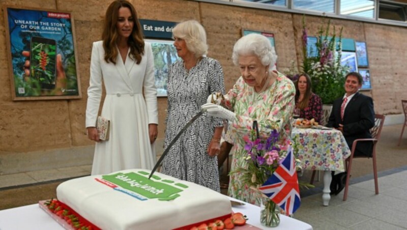 Die Queen ließ es sich nicht nehmen, den Kuchen beim „The Big Lunch“ mit dem Zeremonienschwert des Lord Lieutenant of Cornwall anzuschneiden. (Bild: AP)