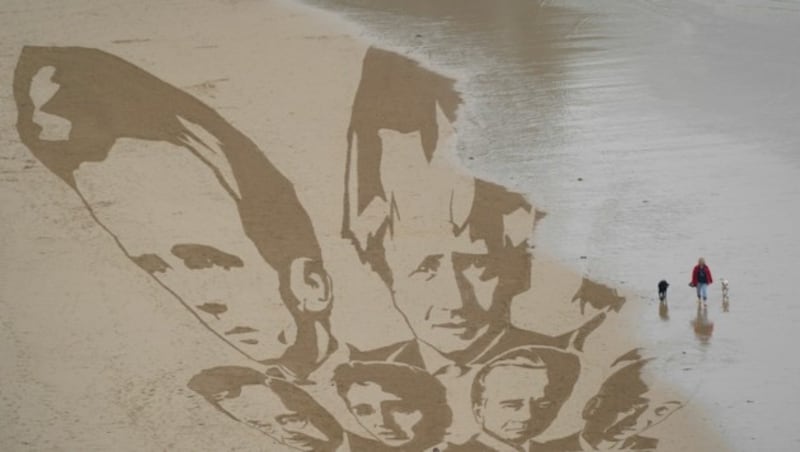 Die steigende Flut erreicht die Köpfe der G7-Staatenlenker, die Aktivisten am Strand von Cornwall in den Sand gezeichnet haben. (Bild: AP)
