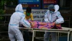 In Sicherheitsmontur bringen diese Spitalsangestellten in Indien einen an Covid-19 verstorbenen Patienten weg. (Bild: AFP)
