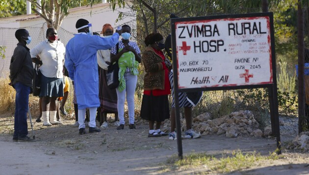 Ein Mitarbeiter eines ländlichen Krankenhauses in Zimbabwe misst die Temperatur von möglichen Corona-Patienten. (Bild: AP)