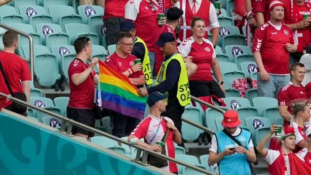 Ordner nehmen dem dänischen Fan die Regenbogenfahne ab. (Bild: AP/Darko Vojinovic)