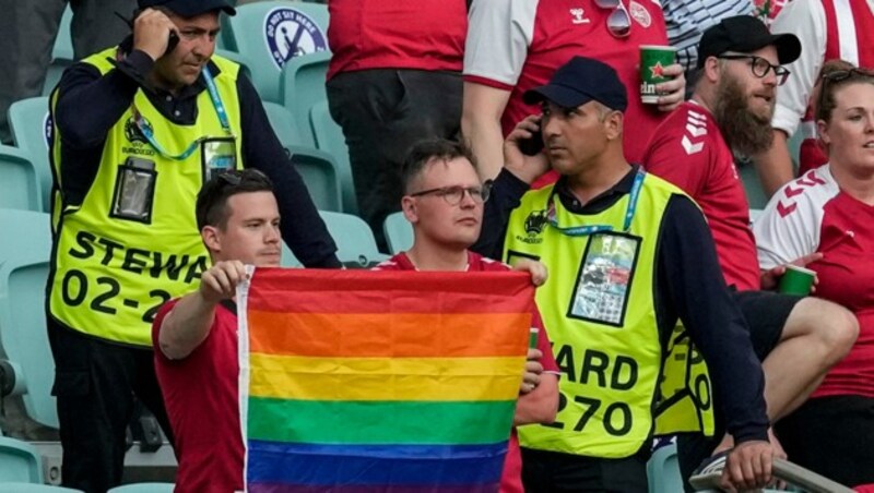 Ordner nähern sich zwei dänischen Fans mit Regenbogenflagge. (Bild: AP)