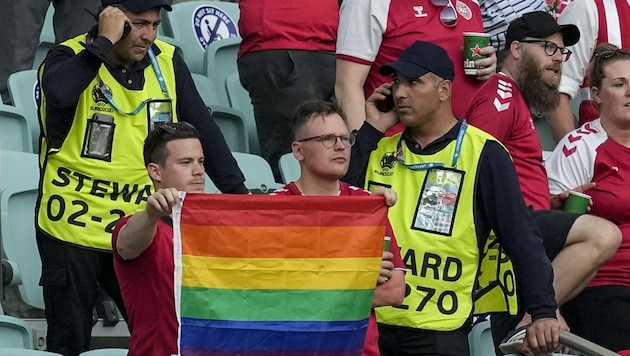 Ordner nähern sich zwei dänischen Fans mit Regenbogenflagge. (Bild: AP)